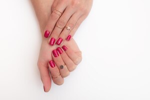 Photo manicure gel polish of viva magenta color with sparkles on female fingers with rings
