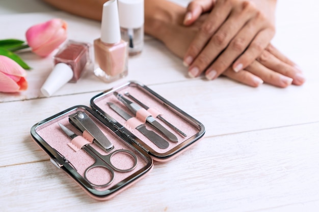 Manicure instruments set with nail polish and women hands