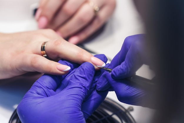 Manicure maakt een manicure bij een klant brengt een tweede laag vernis aan