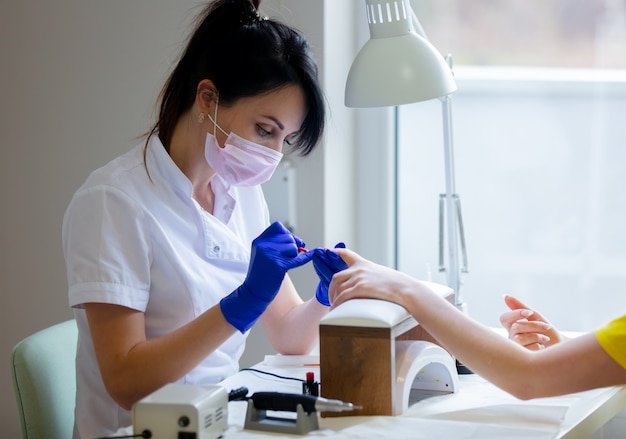 Manicure master applying a nail polish