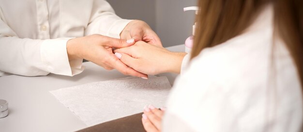 Manicure master massaging female hands before nail procedure in a nail salon.