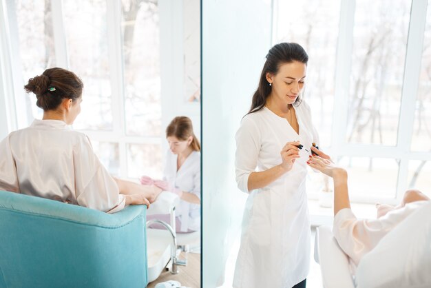 Manicure masters applies nail polish to woman