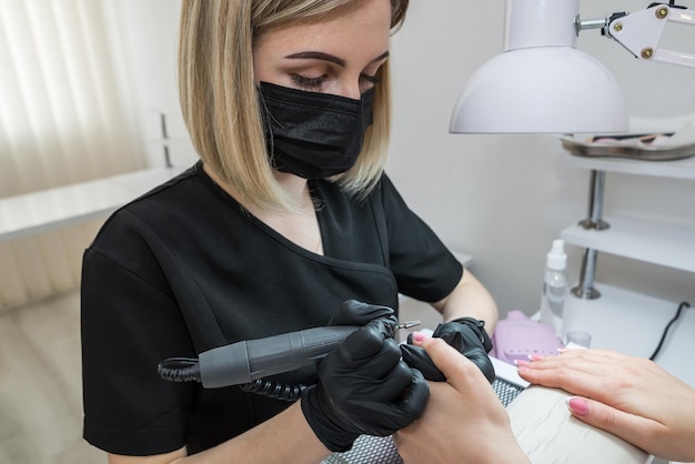 Manicure meester elektrische nagelvijl machine verwijderen van oude nagellak op nagels in een nagelsalon