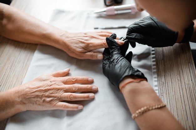 Manicure nagelverzorging doen aan een oudere vrouw, close-up