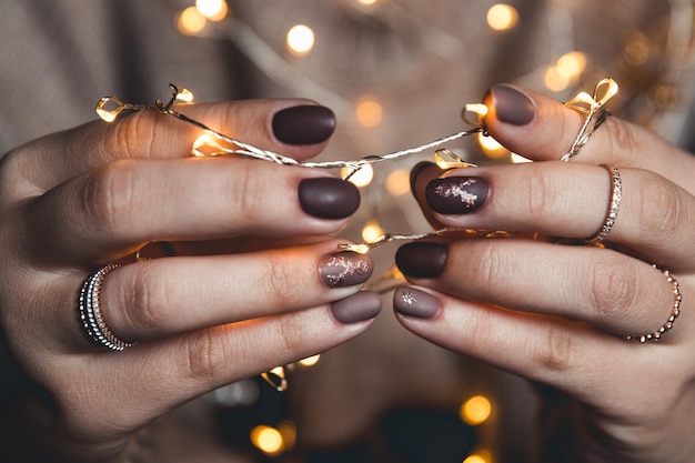 Photo manicure nail art design for new year, christmas cat eye effect black purple golden chameleon shining sparkling on the background of the christmas tree