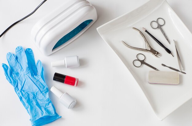 manicure and pedicure items in a white tray, nail polish drying lamp and nail polish