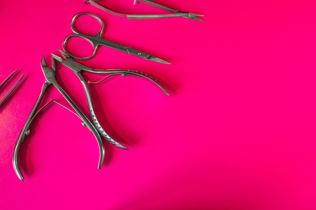 Manicure and pedicure tools on pink background Nail file scissors tweezers pusher nippers Medical tools top view