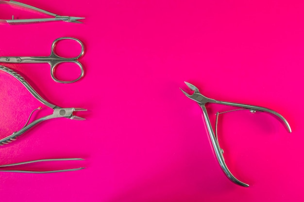 Manicure and pedicure tools on pink background Nail file scissors tweezers pusher nippers Medical tools top view