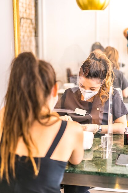 Photo manicure and pedicure with security measures, masks and plastic screens. reopening after the corod-19 pandemic. coronavirus