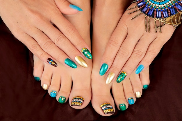 Manicure and pedicure with turquoise color nail polish with\
rhinestones