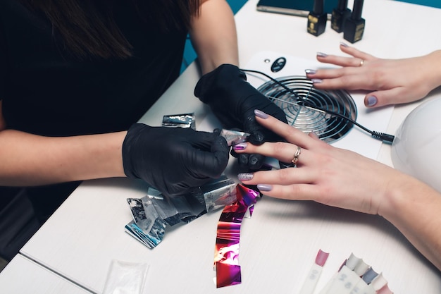 Manicure proces in een schoonheidssalon kleuroverdracht van folie naar nagels