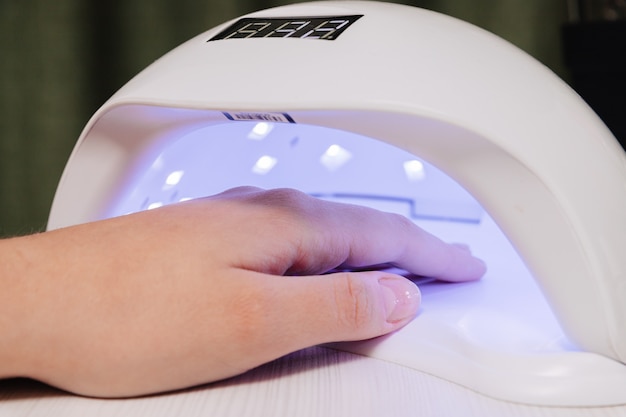 Manicure proces. Nagels drogen in een apparaat met ultraviolette lampen.