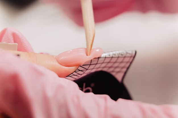 Processo di manicure. il maestro forma un'unghia artificiale da un gel speciale usando un bastoncino di bambù.