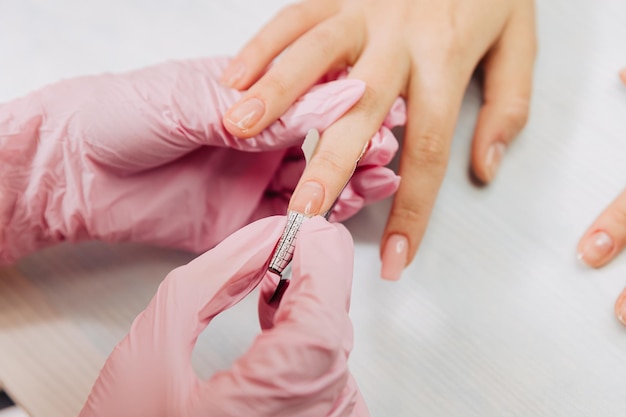 Processo di manicure il maestro forma un'unghia artificiale da un gel speciale usando un bastoncino di bambù