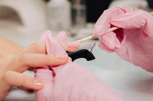 Foto processo di manicure il maestro forma un'unghia artificiale da un gel speciale usando un bastoncino di bambù