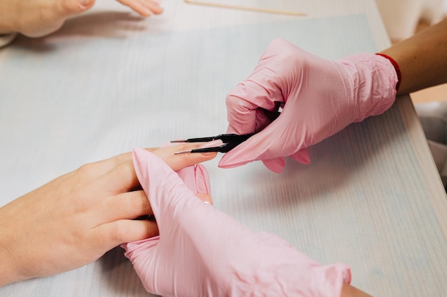 Foto processo di manicure il maestro forma un'unghia artificiale da un gel speciale usando una pinzetta