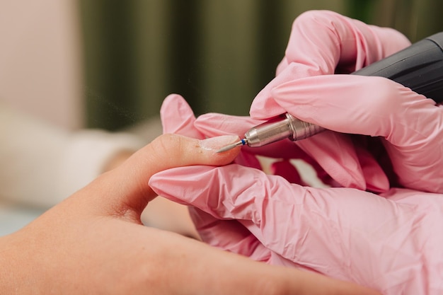 Processo di manicure il maestro lucida l'unghia utilizzando una macchina automatizzata per rimuovere lo smalto