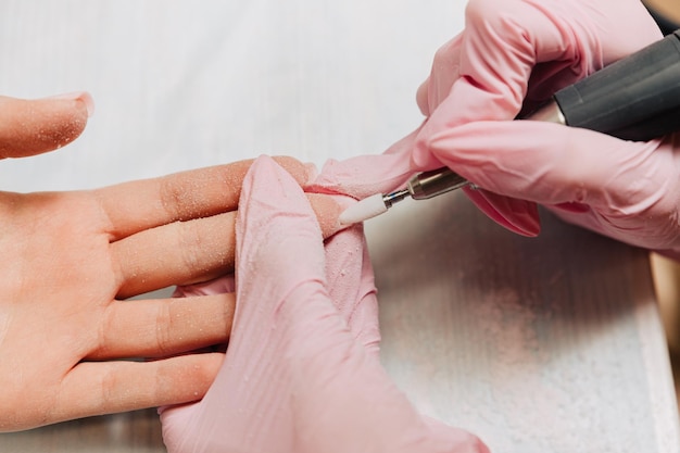 Photo manicure process the master polishes the nail using an automated machine drill polish remover