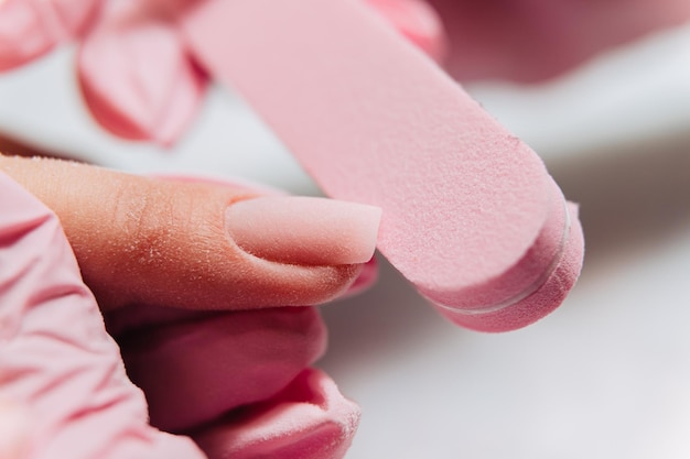 Manicure process The master processes artificial nails with a nail file