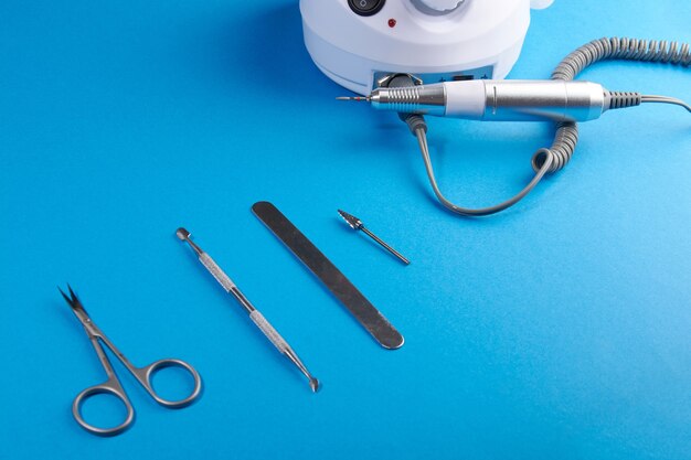 Manicure tools on a blue backgroundscissors pusher cutter saw machine