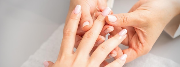 Manicure treatment at beauty spa. A hand of a woman getting a finger massage with oil in a nail salon.