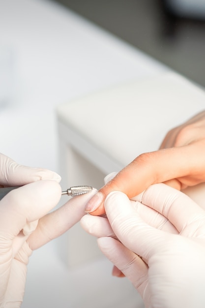 Manicure verwijdert nagellak met behulp van de elektrische machine van de nagelvijl tijdens manicure
