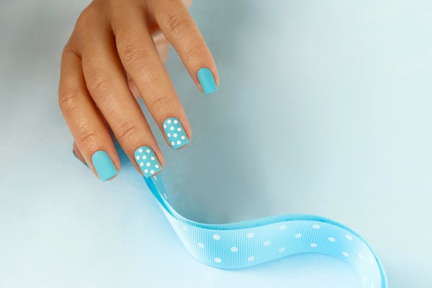 Manicure with dots on the blue color of nail polish.