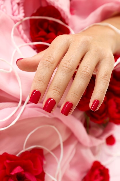 Foto manicure con unghie rosse e petali di rosa.