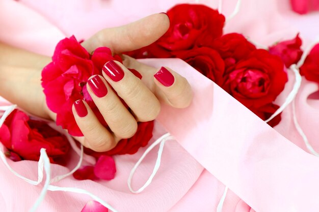 Foto manicure con unghie rosse e petali di rosa.