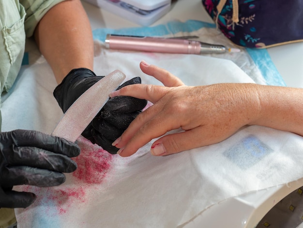 영구적 인 손 페인트 를 위해 오래된 폴라크 를 제거 한 후 파일을 사용하는 매니큐어 여성