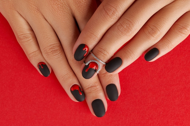 Manicured female hands with fashion accessories trendy autumn halloween bloody spooky nail design