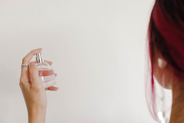 Manicured hands of stylish woman hold perfume in clear white bottle beauty body treatment concept