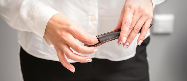 Manicured hands and tools for a manicure. Hands of manicurist take off instrument for a manicure from the leather case in a nail salon.