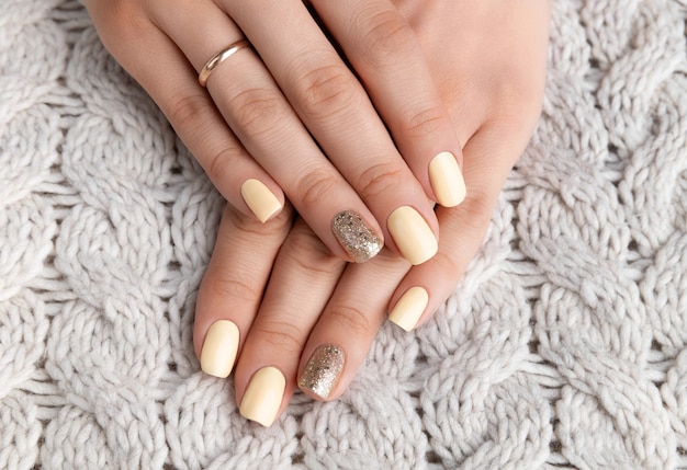 Manicured woman's hands with warm wool beige sweater.
