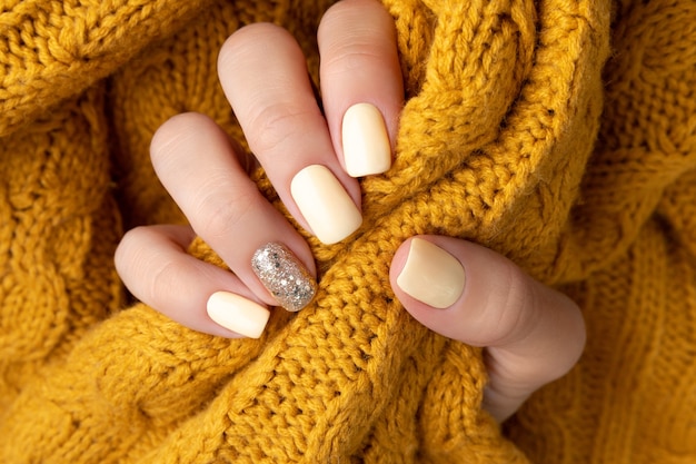 Manicured woman's hands with warm wool yellow sweater.