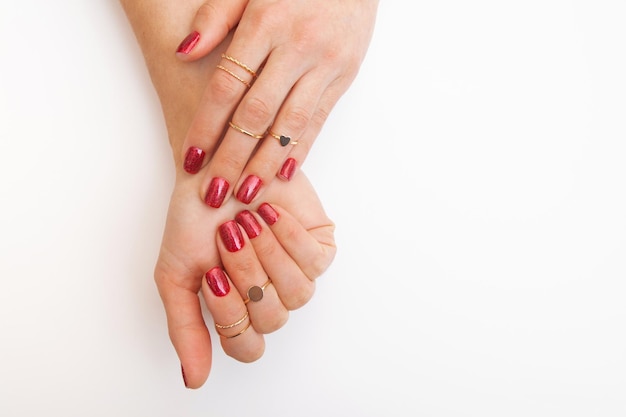 Manicuregellak van rode kleur met glitters op vrouwelijke handen met ringen Bovenaanzicht met kopieerruimte