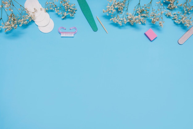 Manicuregereedschappen op een blauwe achtergrond zijn versierd met witte gipskruidbloemen