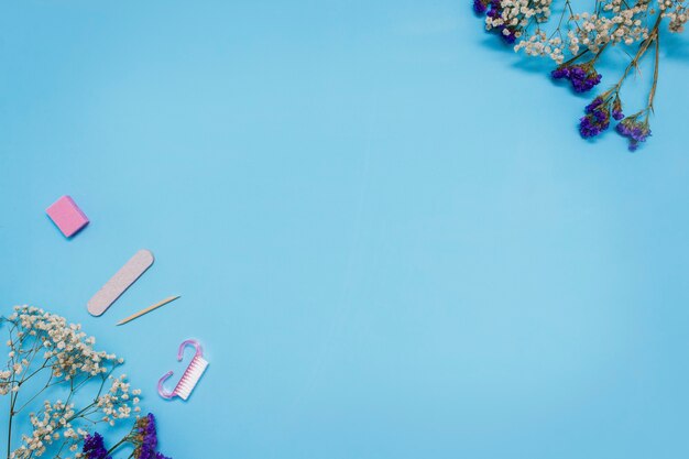 Manicuregereedschappen op een blauwe achtergrond zijn versierd met witte gipskruidbloemen