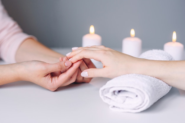 Manicurehanden die massage doen aan de handen van de vrouwelijke cliënt.