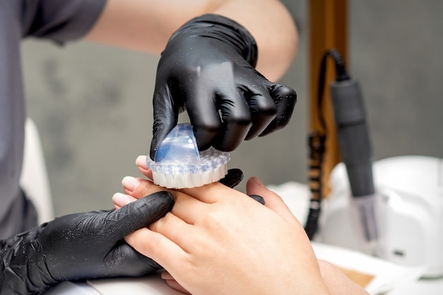 Manicuremeester is stof van vrouwelijke vingernagels in de nagelsalon borstelen