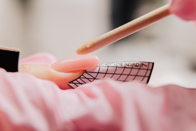 Manicureproces De master vormt een kunstnagel van een speciale gel met behulp van een bamboestok