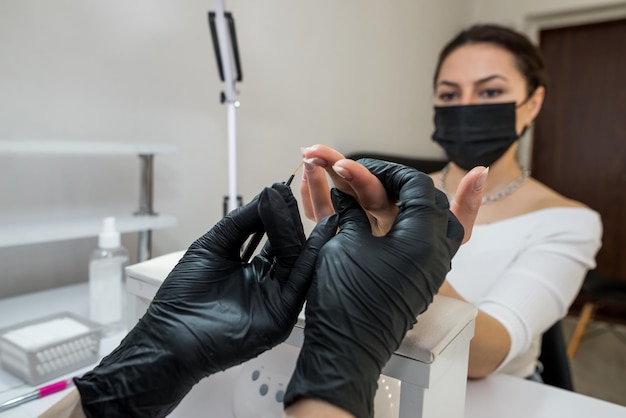 The manicurist covers the client's nails with red varnish Manicure in a beauty salon Nail care concept