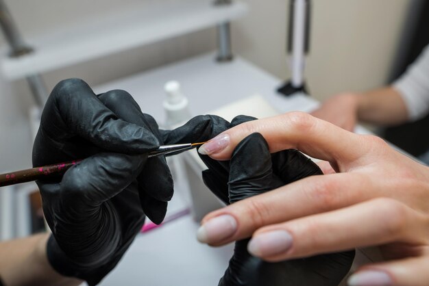 Photo the manicurist covers the client's nails with red varnish manicure in a beauty salon nail care concept