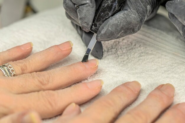 Photo manicurist fixing nails of a client