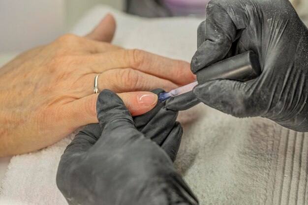 Manicurist fixing nails of a client