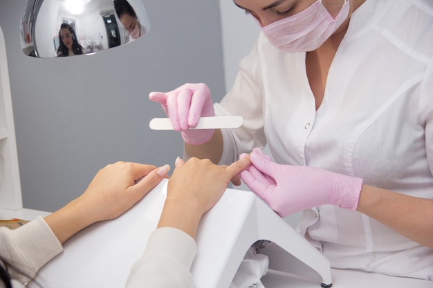 A manicurist gives a manicure to a client. Portrait of an attractive nail salon worker giving a manicure to one of her regular customers