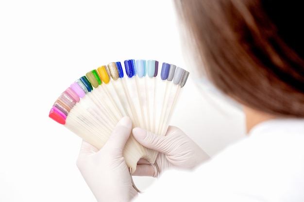 Photo manicurist hands are holding manicure nail color samples palette