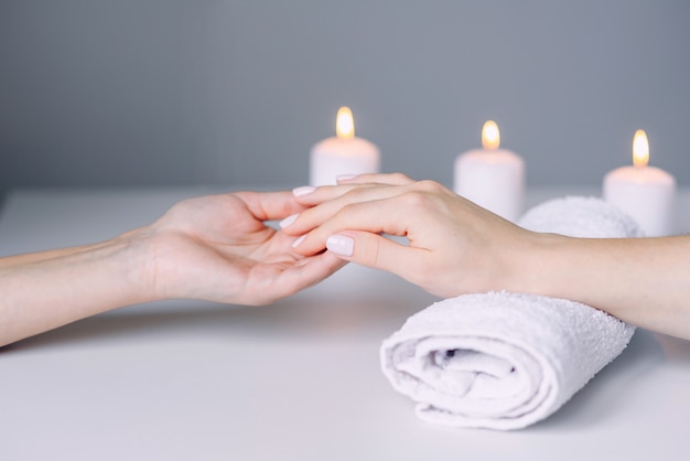 Manicurist hands doing massage from female client's hands. Woman hand receiving manicure procedure.