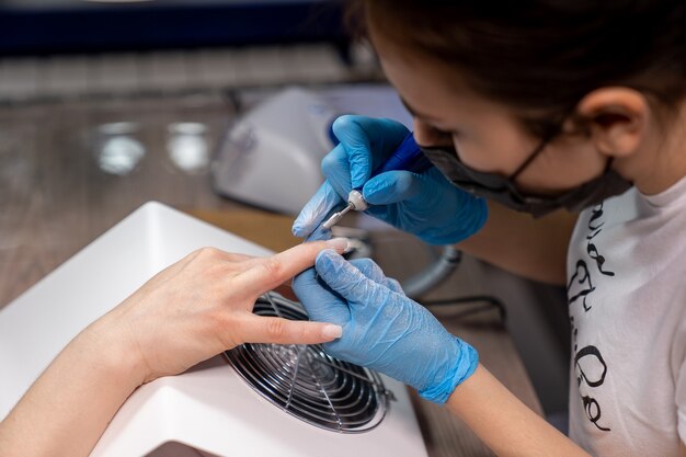 The manicurist is engaged in the treatment of nails before applying gel polish