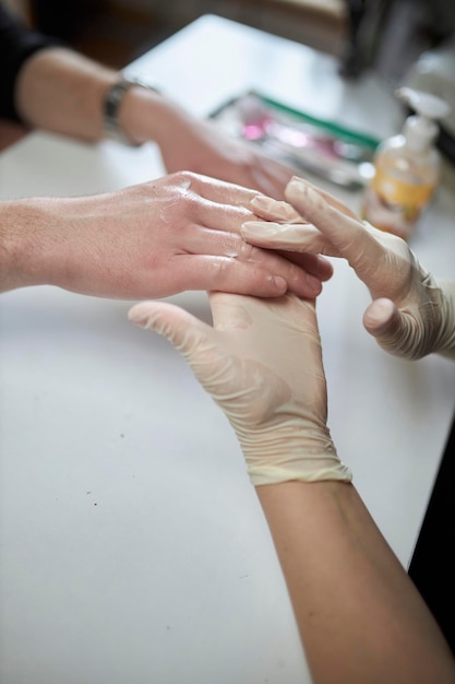 Manicurist makes a manicure for a man male manicure